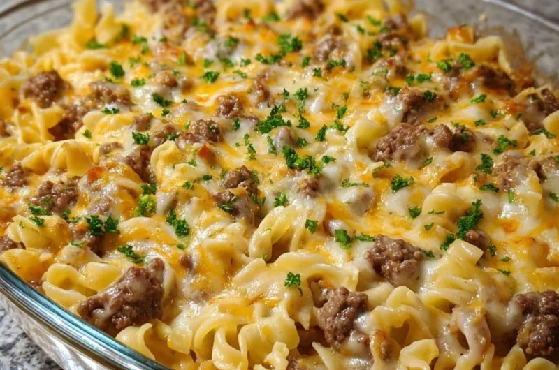Cheesy beef noodle casserole topped with melted cheese and herbs in a baking dish